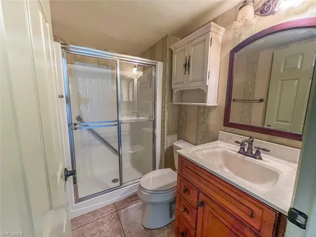 Full bath with a shower stall, toilet, vanity, and tile patterned flooring