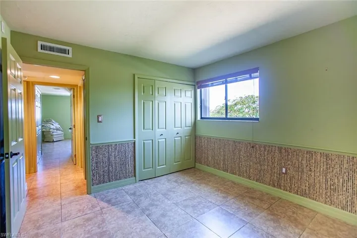 Unfurnished bedroom with wainscoting, baseboards, and a closet