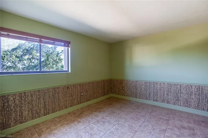 Unfurnished room featuring a wainscoted wall and baseboards