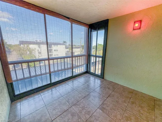 Tiled empty room featuring expansive windows, a textured wall, and a textured ceiling