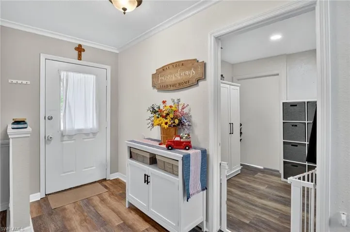 Entryway featuring wood finished floors and ornamental molding