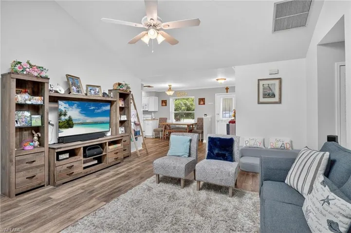 Living room featuring wood finished floors, lofted ceiling, and a ceiling fan