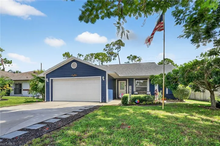 Ranch-style house with an attached garage, driveway, a front yard, and roof with shingles