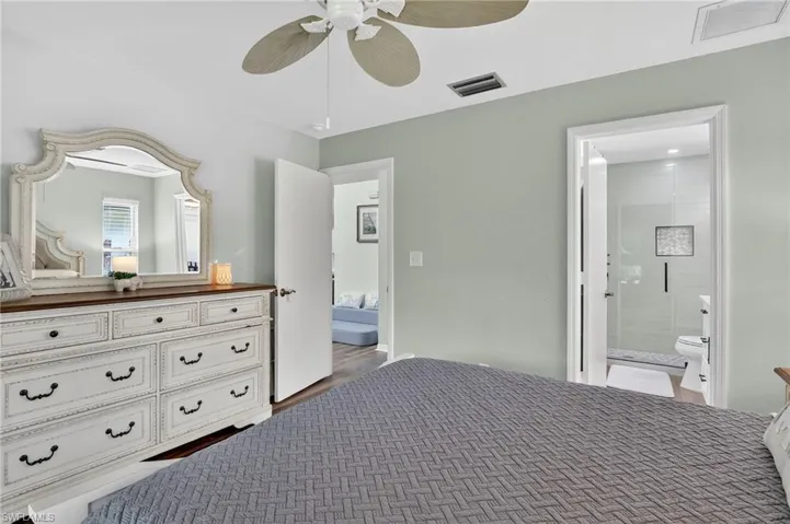 Bedroom featuring connected bathroom, wood finished floors, and ceiling fan