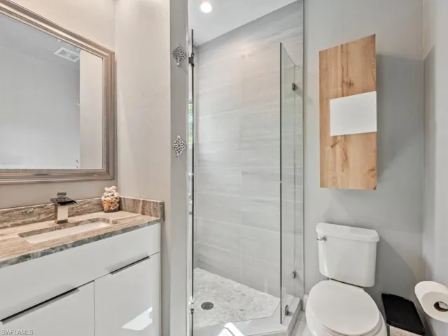 Guest Bathroom featuring toilet, a shower with shower door, and vanity