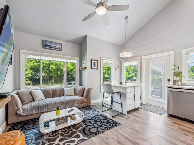 Living room with ceiling fan, high vaulted ceiling, and light hardwood / wood-style flooring