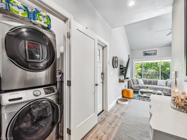 Clothes washing area featuring ceiling fan, stacked washer / drying machine, and light wood-type flooring