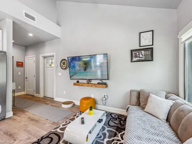 Living room with high vaulted ceiling and light hardwood / wood-style flooring