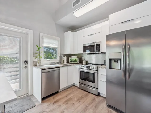 Kitchen with stainless steel appliances, white cabinetry, plenty of natural light, and light wood-type flooring