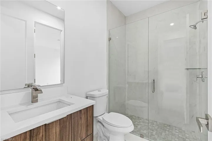 Bathroom with vanity, toilet, and a shower with shower door