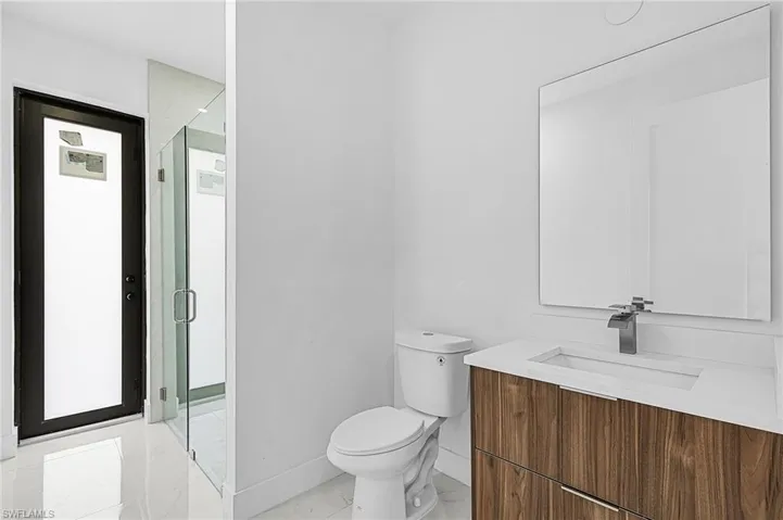 Bathroom with a shower with door, vanity, toilet, and tile patterned flooring