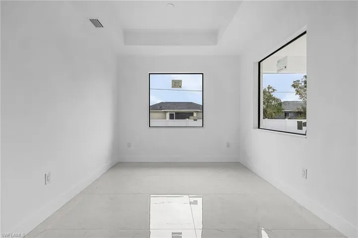 Empty room featuring a tray ceiling and plenty of natural light