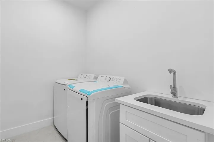 Laundry area featuring sink, washing machine and clothes dryer, and cabinets