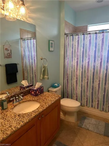 Bathroom featuring a vanity with an integrated sink, granite-style countertop, and wood cabinetry