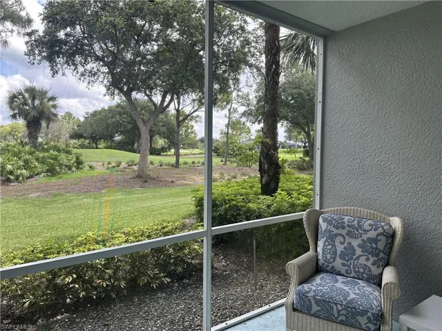 Screened outdoor patio featuring a textured wall finish, a palm tree, and a lush green landscape beyond