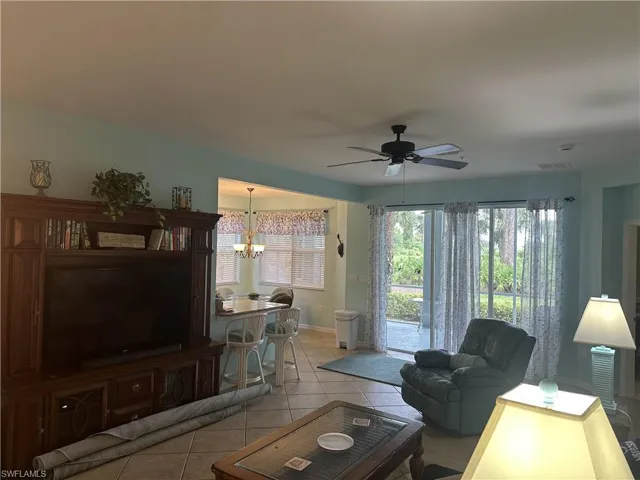 Spacious living area featuring tile flooring, a ceiling fan, and sliding glass doors providing outdoor access