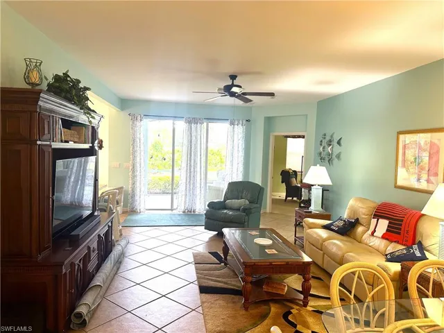 Spacious living area featuring tile flooring, a ceiling fan, and sliding glass doors providing access to the outdoors