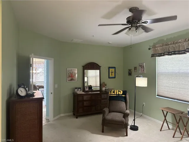 Spacious room featuring light green wall paint, a ceiling fan with integrated lighting, and light-colored carpeting