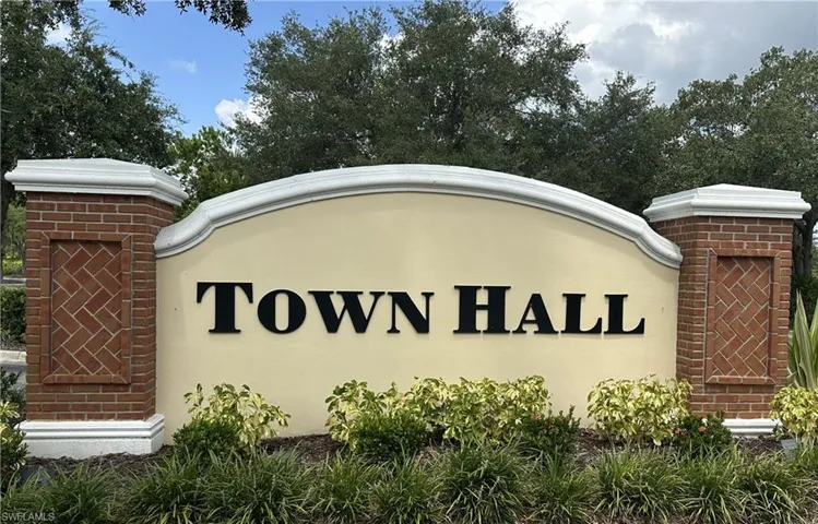Entry monument featuring brick columns with herringbone accents, a cream-colored facade, and dimensional lettering, surrounded by established landscaping