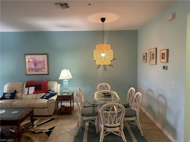 Open-concept living and dining area featuring tile flooring, a woven pendant light fixture, and light blue wall tones