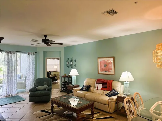 Spacious interior with tile flooring throughout, featuring a ceiling fan and sliding glass door access to an outdoor area