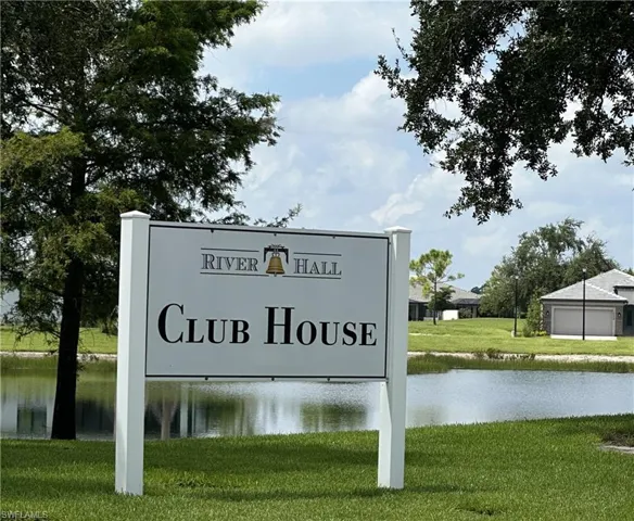 River Hall Club House signage with a reflective pond and green landscaping