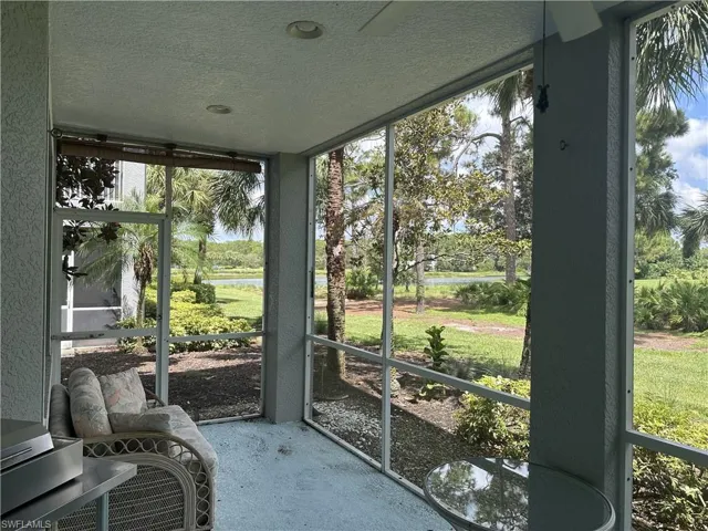 Screened lanai featuring a textured concrete floor, recessed lighting, and a tranquil water feature backdrop