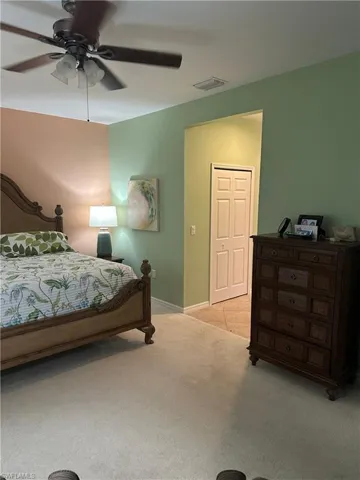 Carpeted bedroom featuring a ceiling fan with light kit, a light-toned wood bed frame, and a dark wood-finish dresser
