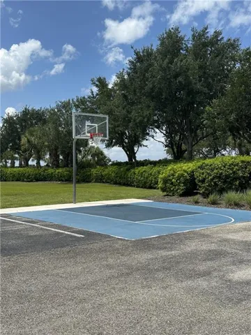 Outdoor basketball court featuring a clear backboard and blue-painted playing surface