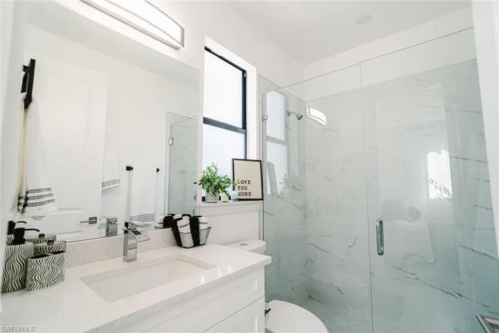 Bathroom featuring vanity, toilet, and a shower with door