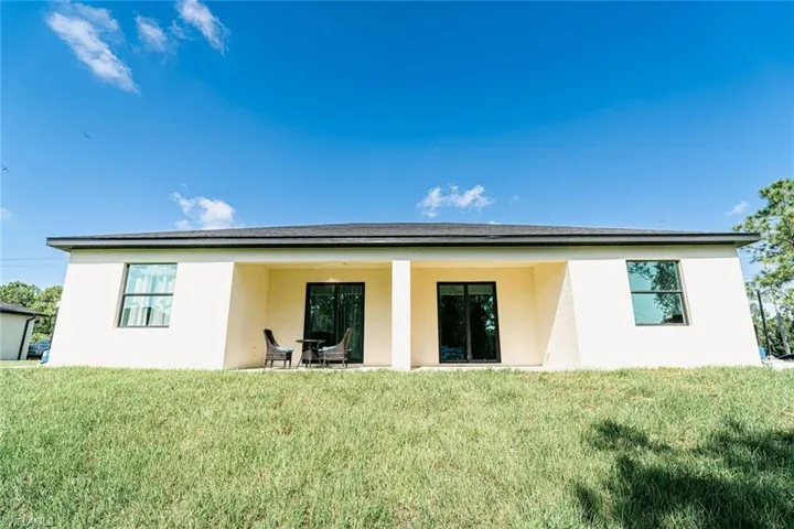 Rear view of property featuring a lawn and a patio