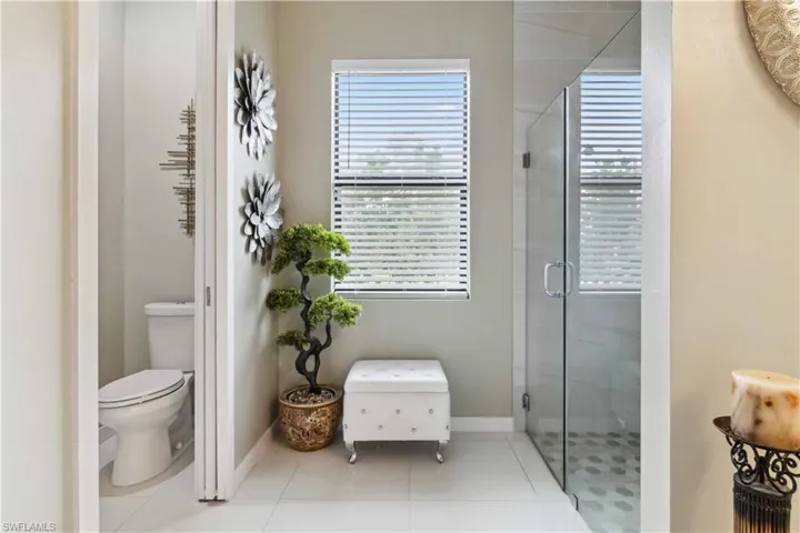 Bathroom featuring toilet, a shower with door, and tile patterned floors