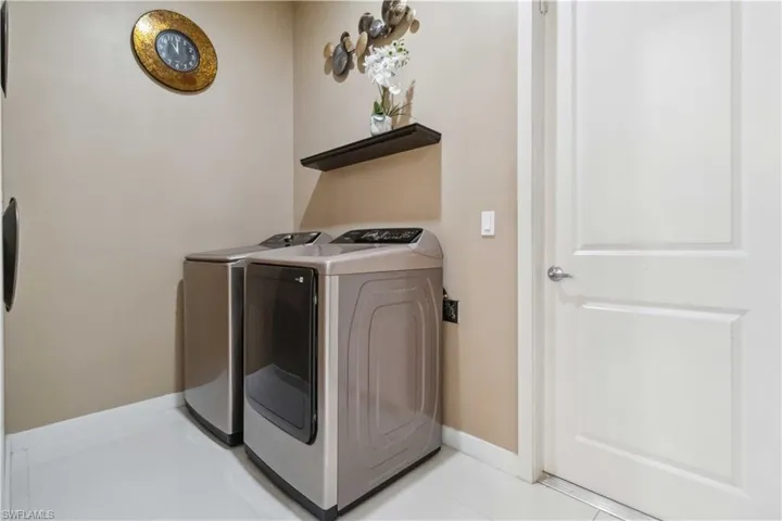 Washroom featuring washing machine and dryer and light tile patterned floors