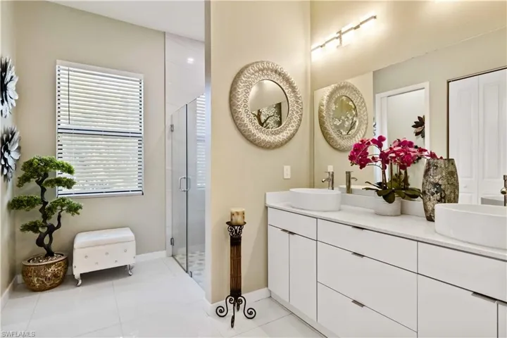 Full bathroom featuring double vanity, light tile patterned flooring, and a shower stall