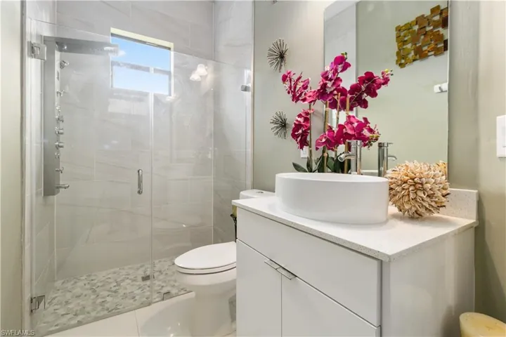 Bathroom with a shower with door, tile patterned floors, toilet, and vanity