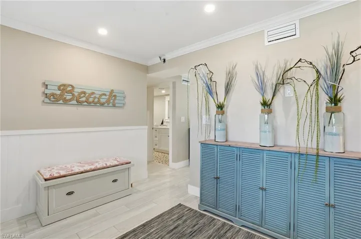 Hall with ornamental molding, a wainscoted wall, recessed lighting, and wood finished floors