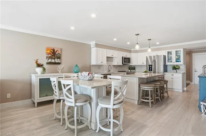 Kitchen featuring a kitchen island, a breakfast bar area, crown molding, backsplash, and hanging light fixtures