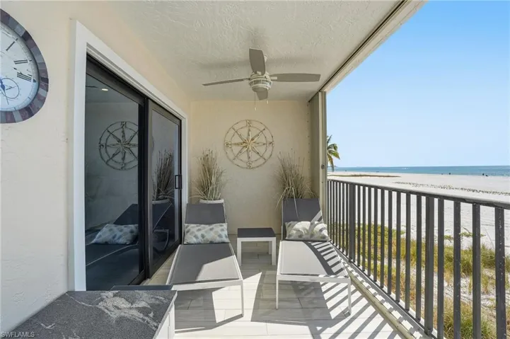 Balcony with view of water and beach and ceiling fan