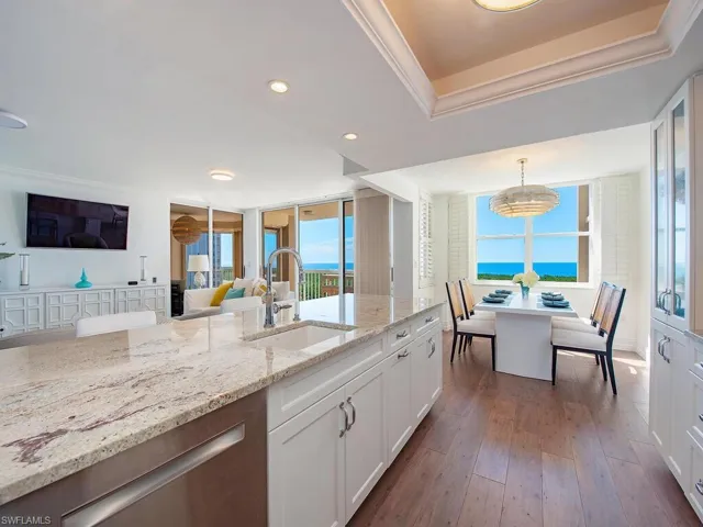 Kitchen featuring white cabinets, recessed lighting, ornamental molding, light stone countertops, and dark wood-style flooring