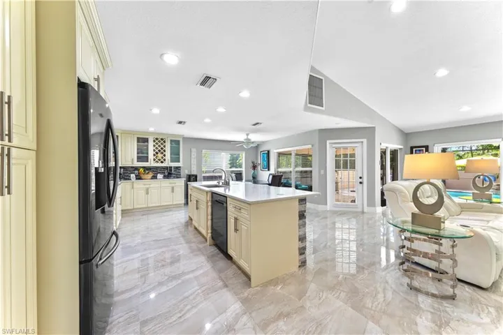 Kitchen featuring ceiling fan, an island with sink, fridge with ice dispenser, sink, and cream cabinets
