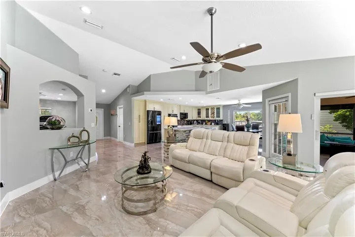 Living room featuring ceiling fan and high vaulted ceiling