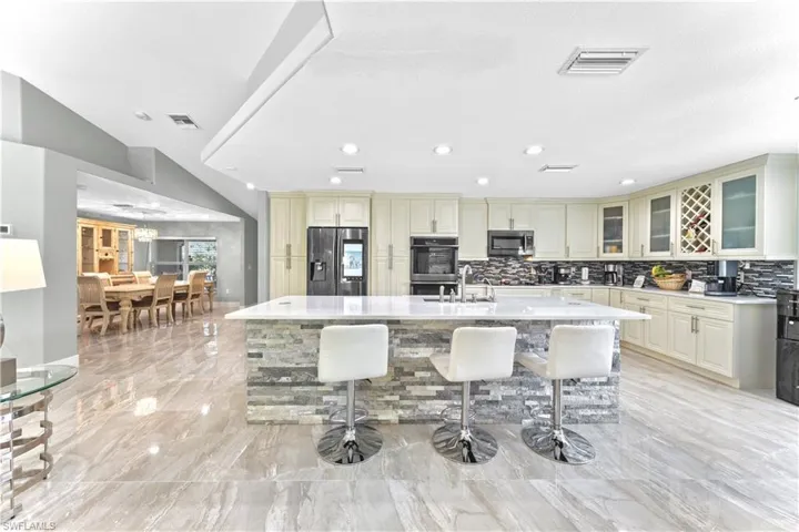 Kitchen with a kitchen breakfast bar, cream cabinetry, a center island with sink, and stainless steel appliances