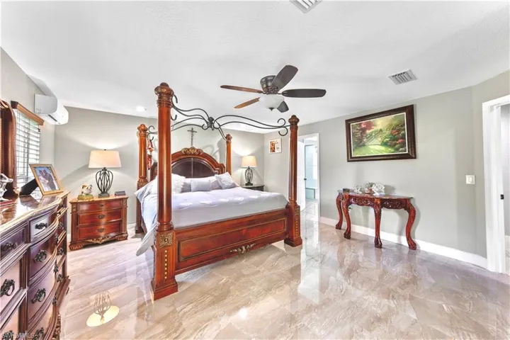 Bedroom with a textured ceiling, ceiling fan, and a wall mounted air conditioner