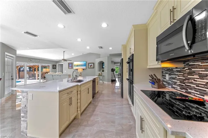 Kitchen with black appliances, cream cabinets, and sink