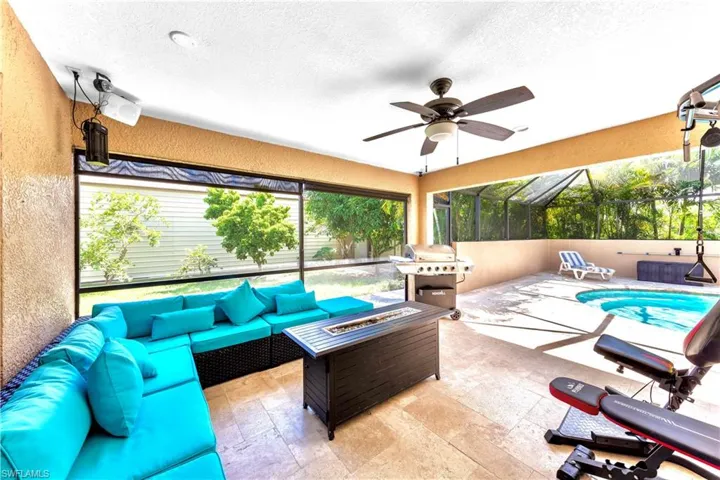 View of patio / terrace featuring ceiling fan, area for grilling, an outdoor living space with a fire pit, and glass enclosure