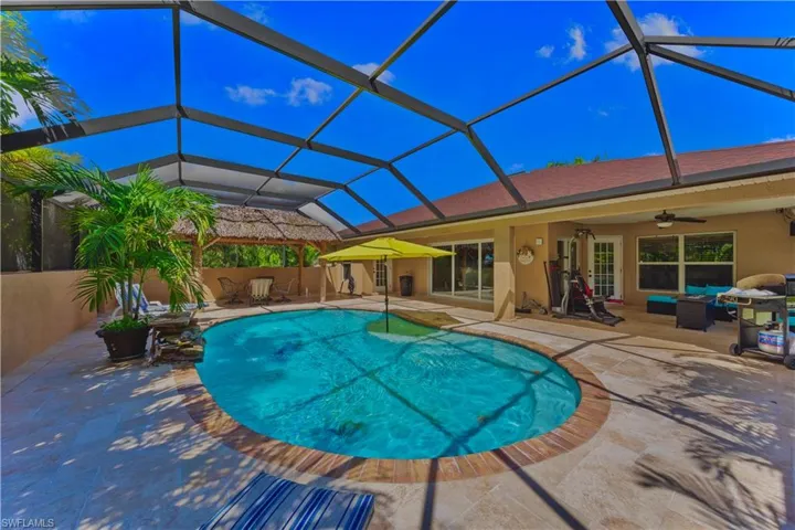View of swimming pool featuring ceiling fan, glass enclosure, and a patio