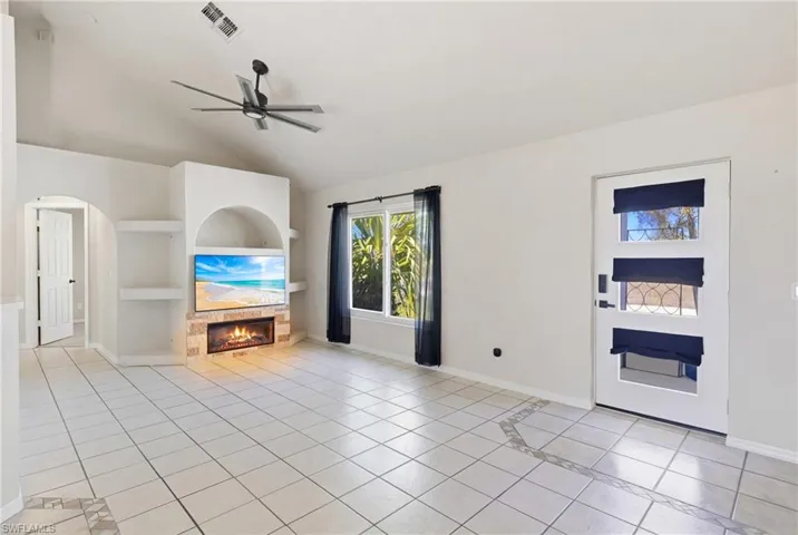 An expansive, light-filled living space designed for both comfort and entertaining, featuring a cozy fireplace and a custom built-in entertainment center—the perfect setting for relaxing evenings or hosting guests.