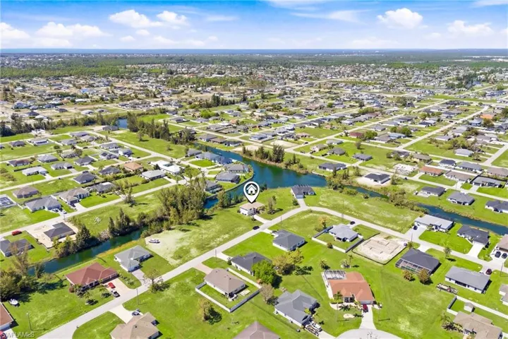 Aerial shot capturing the charm and serenity of the surrounding area, revealing the quiet streets, lush landscaping, and proximity to canals and waterfront living.Option 5:Panoramic neighborhood view from above, highlighting the home’s placement in a peaceful community filled with greenery, scenic waterways, and a quintessential Florida lifestyle.I can now take all the photo descriptions you’ve given me so far—front, blue door, entryway, staircase, living room, dining, kitchen, loft, bedrooms, lan