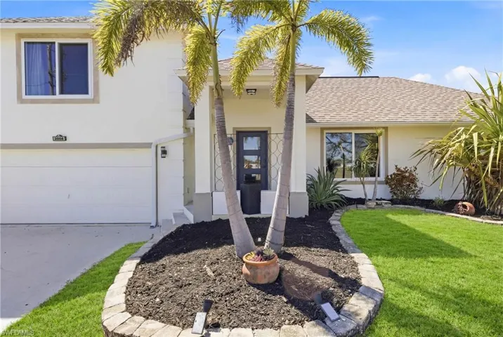 A picture-perfect Florida entrance with manicured greenery and vibrant palms, framing a move-in ready home that radiates charm and sophistication.