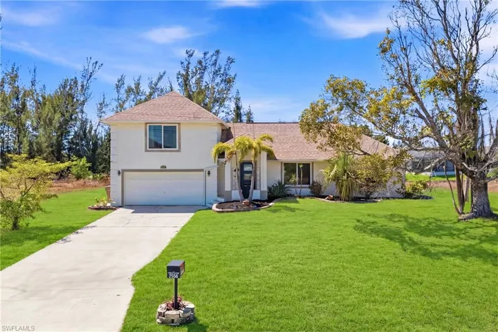 A stunning first impression—this beautifully maintained two-story home welcomes you with lush tropical landscaping, swaying palms, and vibrant greenery, setting the tone for your own private Florida oasis.